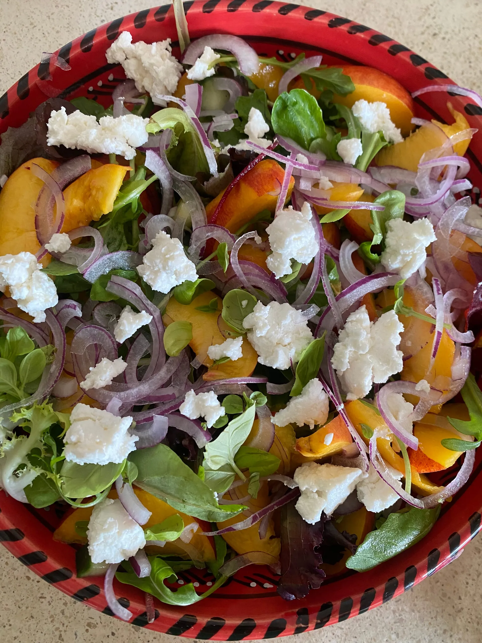 A salad of sliced peaches, crumbled goat’s cheese, red onion and leaves
