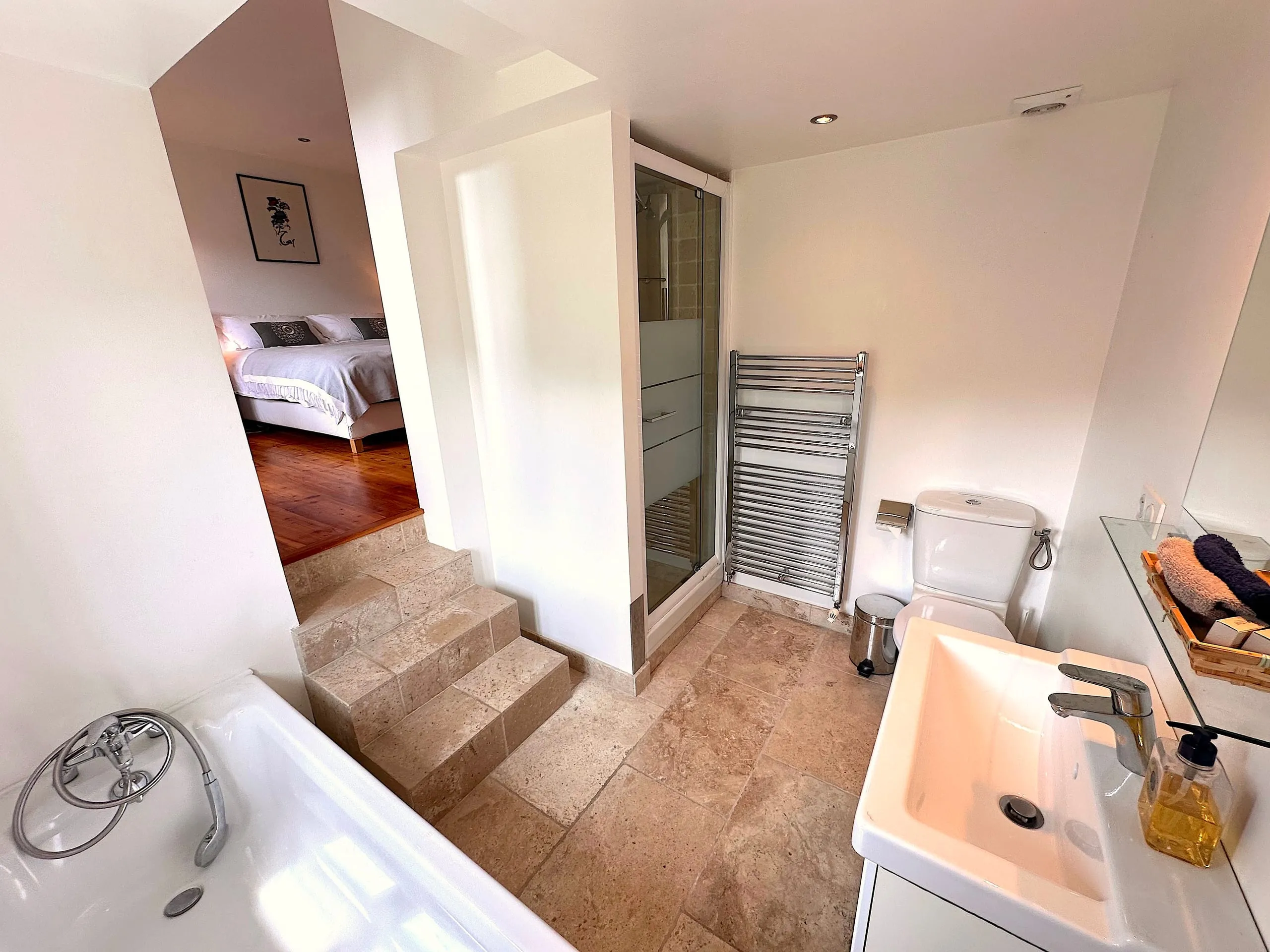 The ensuite bathroom of bedroom one, with a bath, a separate shower and steps up to the bedroom