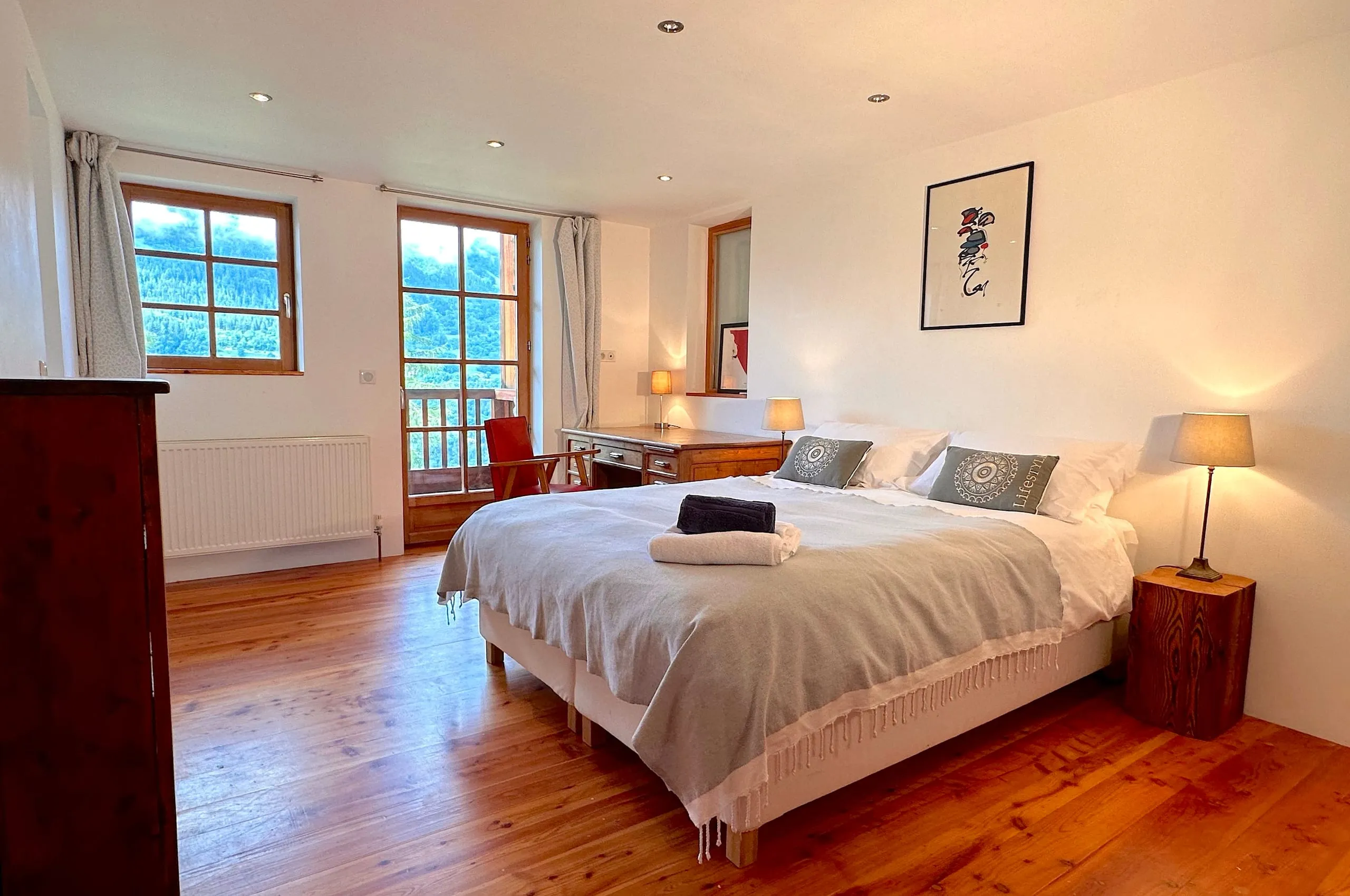 Bedroom one, with a large bed, a writing desk and two windows onto the mountainside