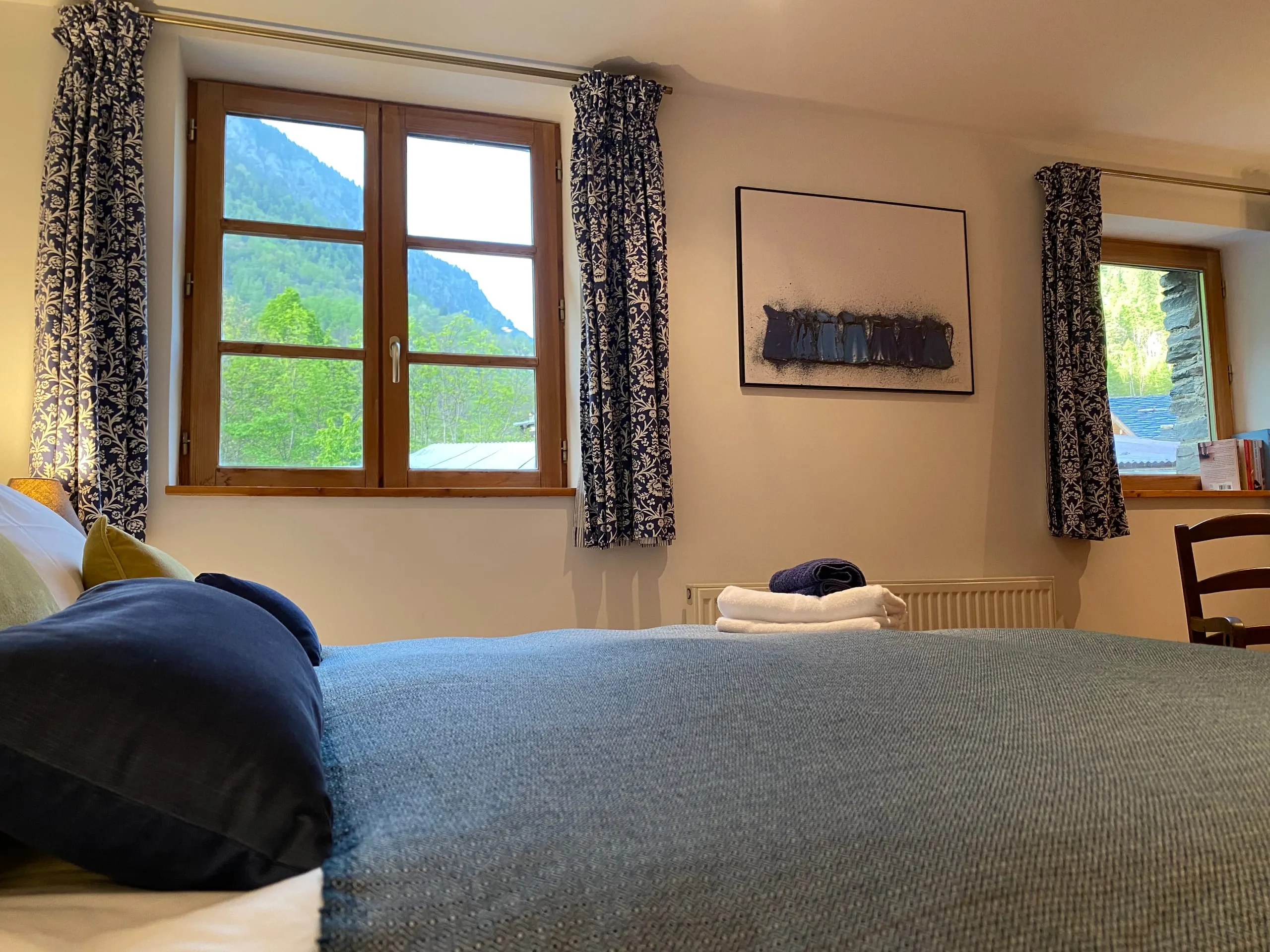The view from the bed in bedroom four, two windows onto the wooded mountainside